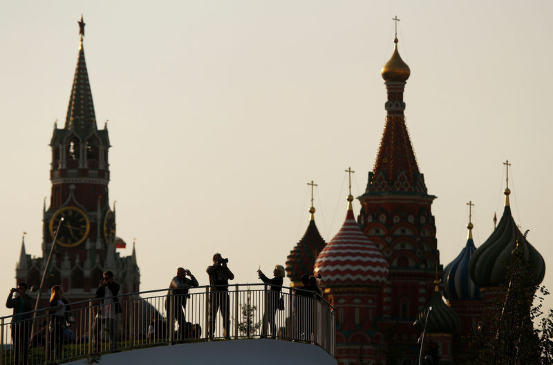 © Reuters. FILE PHOTO: People take pictures at the newly opened Zaryadye Park off Red Square, with the Spasskaya Tower and St. Basil's Cathedral seen in the background, in central Moscow