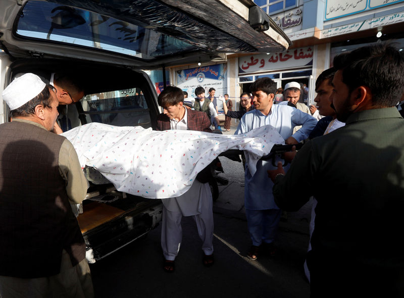 © Reuters. Afghan men carry a dead body of a victim inside an ambulance near the site of a suicide bomb blast in Kabul
