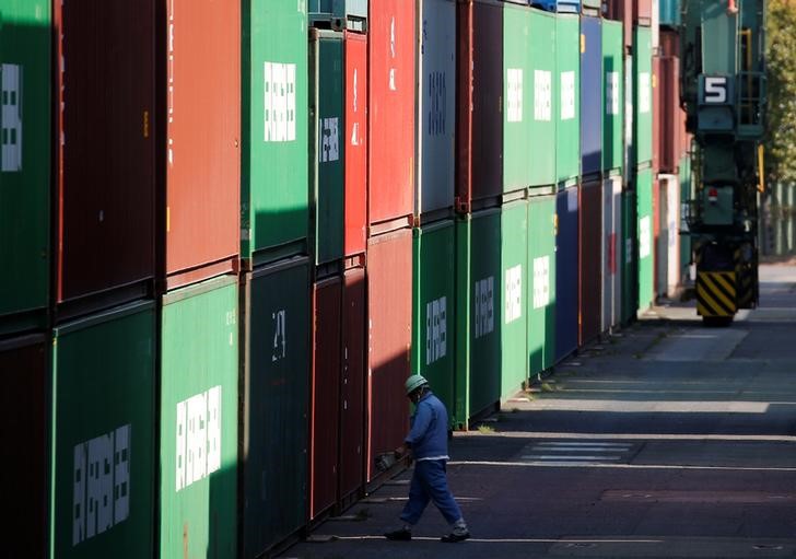 © Reuters. A worker walks between shipping containers at a port in Tokyo