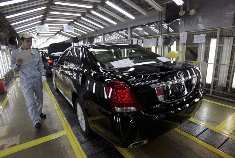 © Reuters. FILE PHOTO: An employee walks past as he checks on newly-produced cars at a Toyota factory in Tianjin