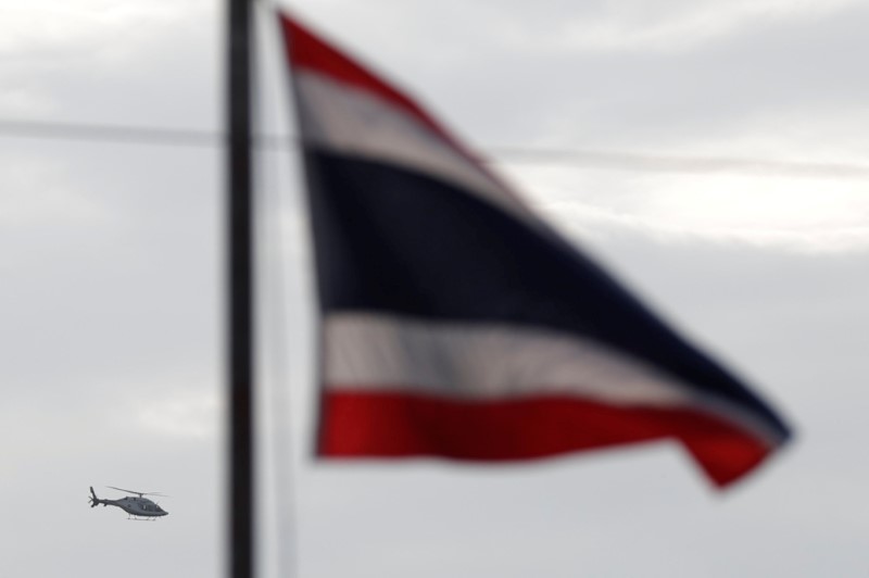 © Reuters. A helicopter carrying rescued schoolboys flies past a Thailand national flag in Chiang Rai