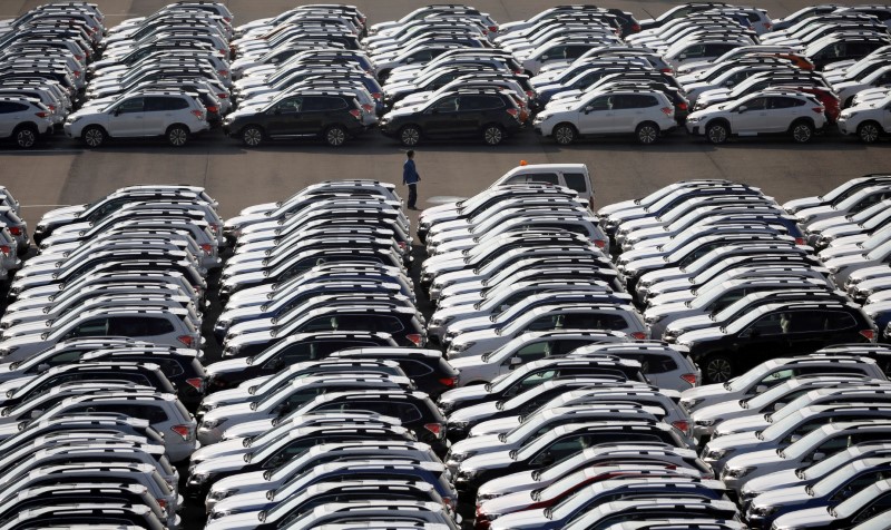© Reuters. FILE PHOTO A worker is seen among newly manufactured cars awaiting export at port in Yokohama