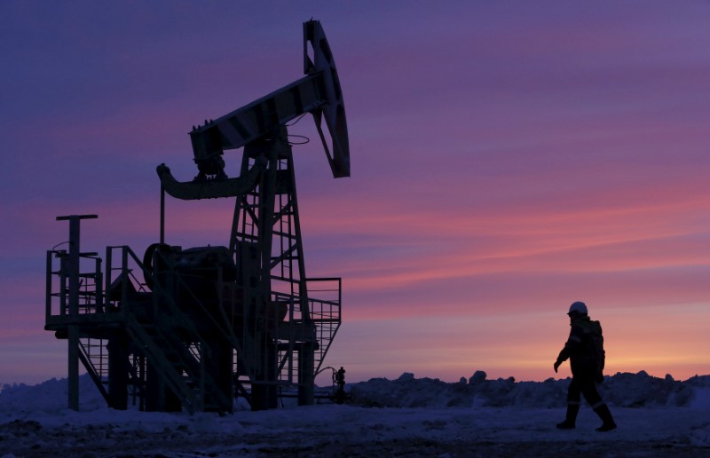 © Reuters. FILE PHOTO: File photo of a worker walking past a pump jack on an oil field owned by Bashneft, Bashkortostan
