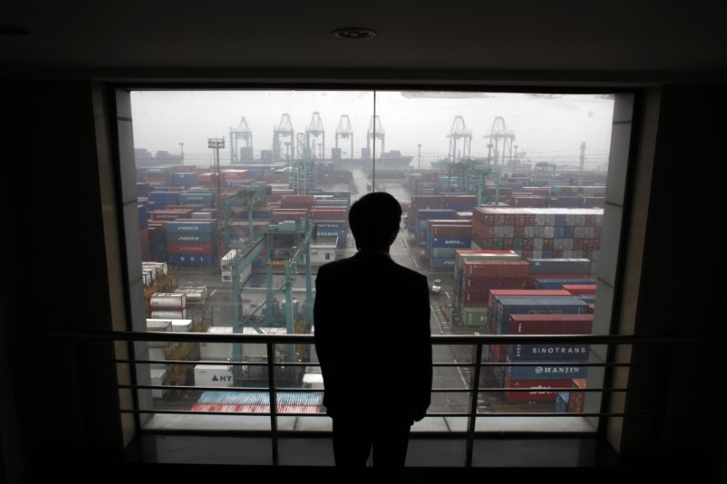 © Reuters. An employee views the Port of Shanghai from an office window