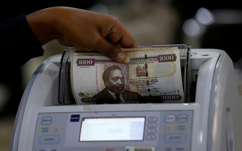 © Reuters. FILE PHOTO: A Kenya Commercial Bank Mtaani agent counts Kenya shilling notes on a money counting machine as she serves a client inside in the banking hall at the Kencom branch in Nairobi