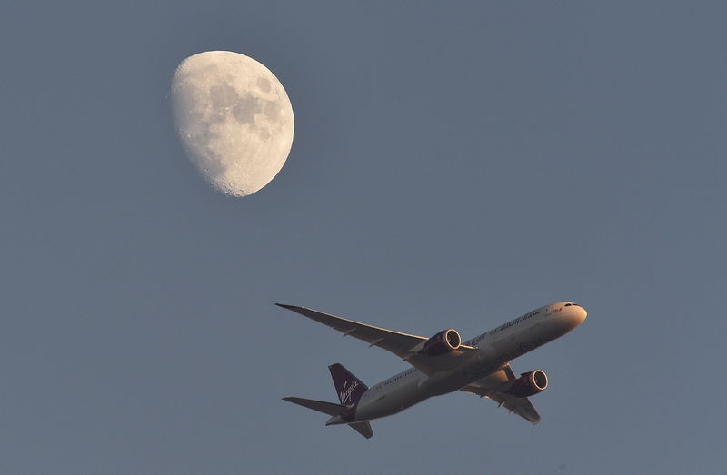 © Reuters. FILE PHOTO: A Virgin Atlantic passenger plane flies in the sky with the moon seen in the background, in London, Britain