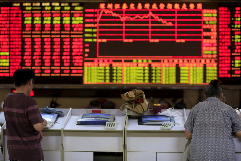 © Reuters. Investors look at computer screens in front of an electronic board showing stock information at a brokerage house in Shanghai