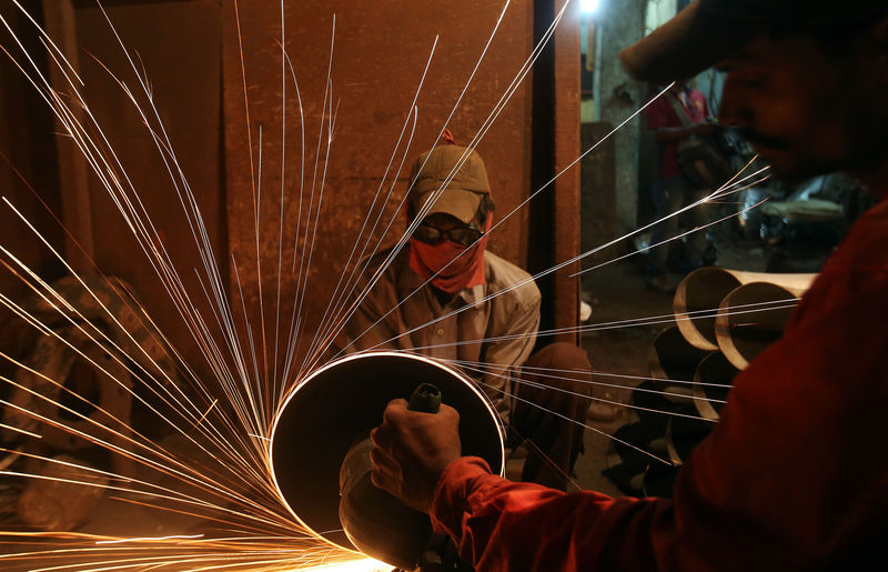 © Reuters. FILE PHOTO:  A worker cuts metal inside a workshop manufacturing metal pipes in Mumbai