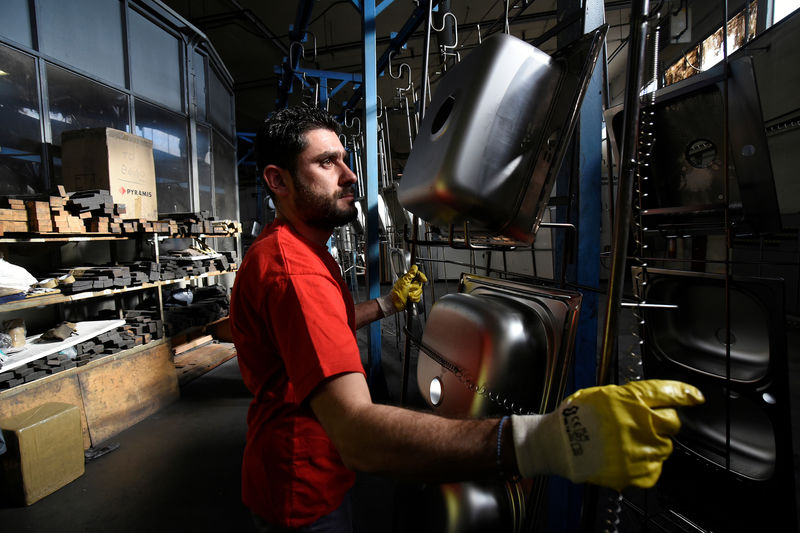 © Reuters. FILE PHOTO:  A worker carries stainless steel sinks at the Pyramis Metallourgia manufacturing facility in Thessaloniki