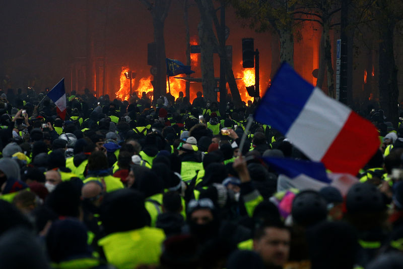 © Reuters. A French flag is held by protesters wearing yellow vests, a symbol of a drivers' protest against higher diesel taxes, who demonstrate near the Place de l'Etoile in Paris