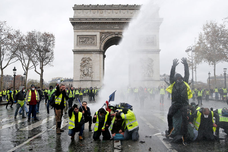 © Reuters. FILE PHOTO: Protesters wearing yellow vests, a symbol of a French drivers' protest against higher diesel taxes, stand up in front of a police water canon at the Place de l'Etoile near the Arc de Triomphe in Paris