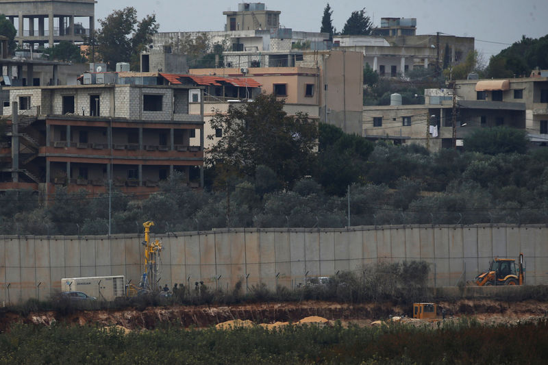 © Reuters. Israeli military personnel and a drill are seen as they work next to the border with Lebanon, in the town of Metulla, northern Israel