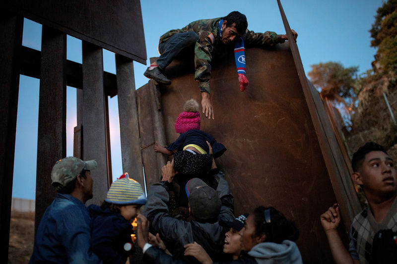 © Reuters. Imigrantes de Honduras que fazem parte de caravana a caminho dos EUA pulam cerca na fronteira do México com os EUA na cidade mexicana de Tijuana