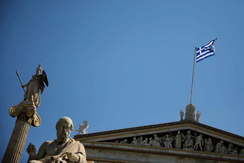 © Reuters. FILE PHOTO: A Greek national flag flies atop the Athens Academy next to the statues of ancient goddess Athena and Greek philosopher Plato in Athens