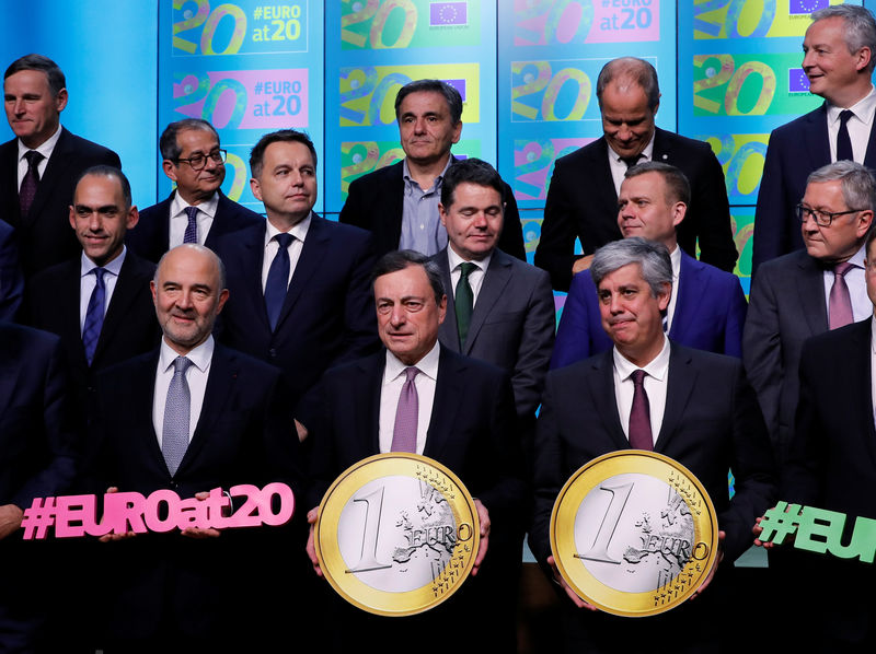 © Reuters. ECB President Draghi and eurozone finance and economy ministers take part in a group photo while celebrating the 20th anniversary of the euro during a eurozone finance ministers meeting in Brussels