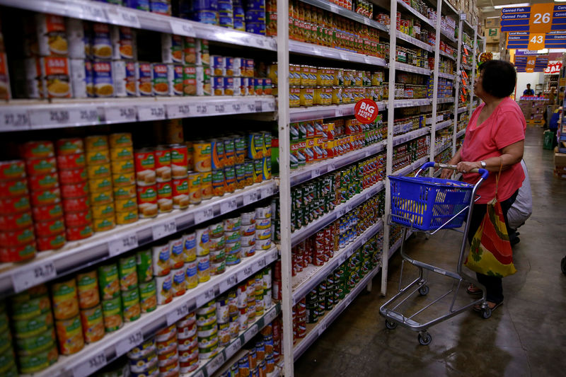 © Reuters. FILE PHOTO:  Woman scans the selection of canned goods at a grocery store in Makati