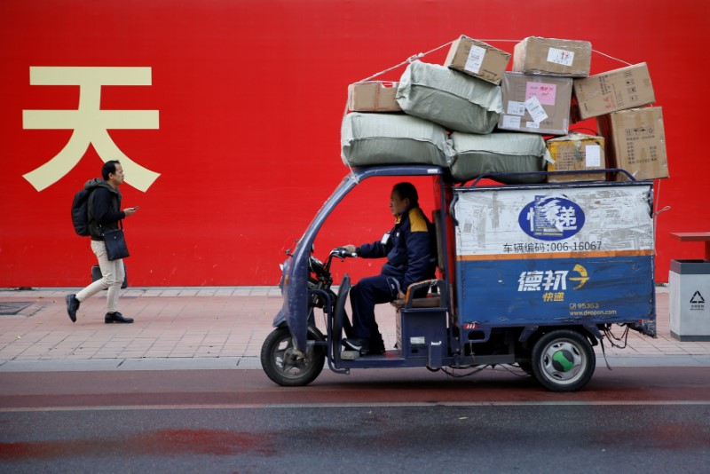 © Reuters. An electric delivery vehicle of Deppon Logistics drives past a banner with a government slogan in Beijing