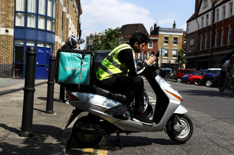 © Reuters. A Deliveroo scooter driver takes a break between deliveries in London