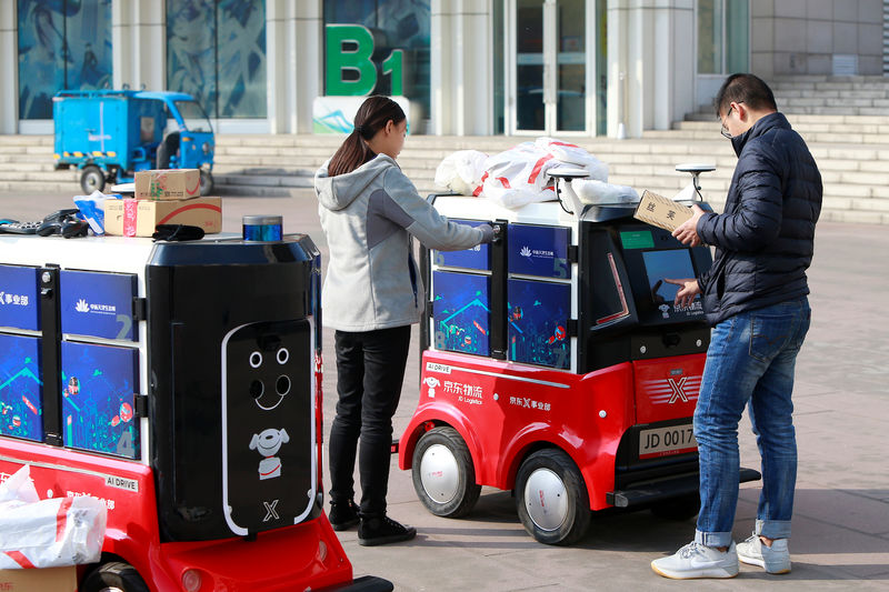 © Reuters. Pessoas retiram encomendas de robô de entregas autônomo da JD.com em Tianjin, China