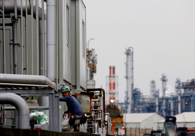 © Reuters. FILE PHOTO : A worker is seen in front of facilities and chimneys of factories at the Keihin Industrial Zone in Kawasaki