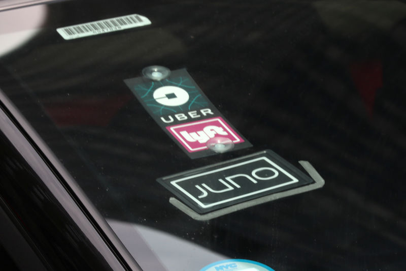 © Reuters. The Uber Lyft and Juno logos are seen on a car as it drive up 6th Avenue in New York City