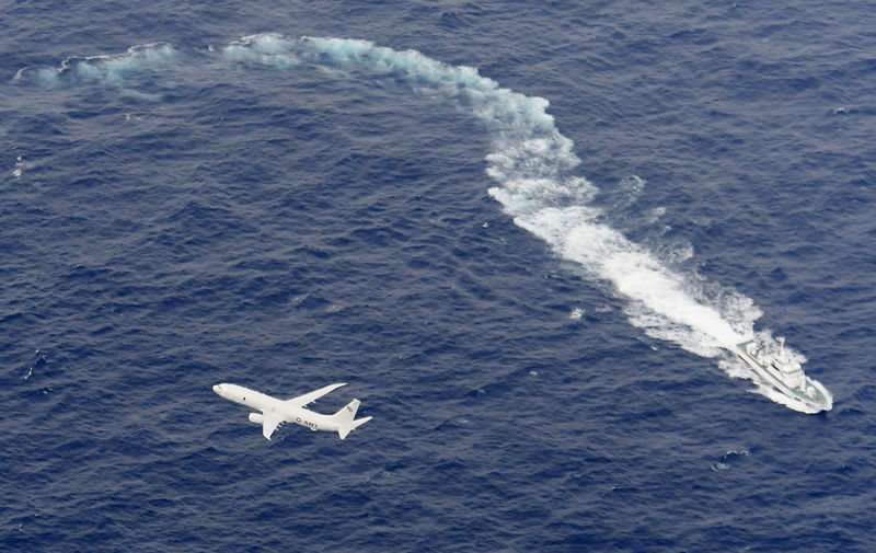 © Reuters. Navio de patrulha da Guarda Costeira japonesa e avião da Marinha dos EUA durante operação de busca a fuzileiros desaparecidos no litoral do Japão