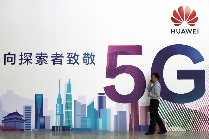 © Reuters. Man talks on his phone beside a Huawei's billboard featuring 5G technology at the PT Expo in Beijing