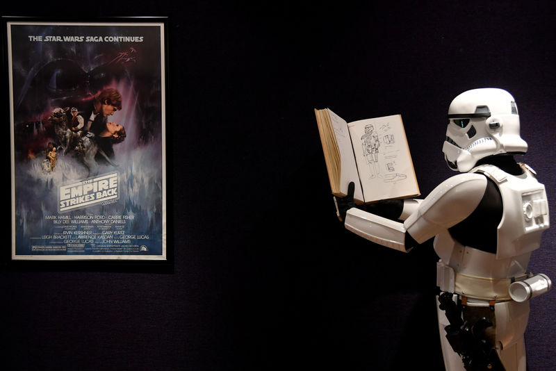 © Reuters. Un hombre vestido con un traje de soldado imperial se para frente a un póster de la secuela de Star Wars "The Empire Strikes Back" que pertenece al diseñador de vestuario John Mollo, durante una sesión fotográfica antes de una subasta en Bonhams en el centro de Londres, Reino Unido