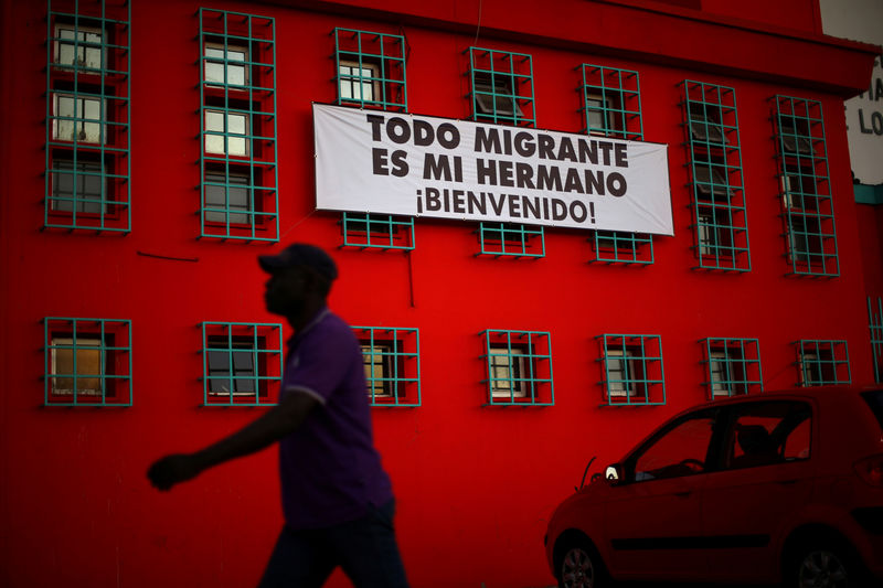 © Reuters. FILE PHOTO: An Haitian immigrant walks past a banner that reads "All immigrant is my brother. Welcome!", outside a church in Santiago,