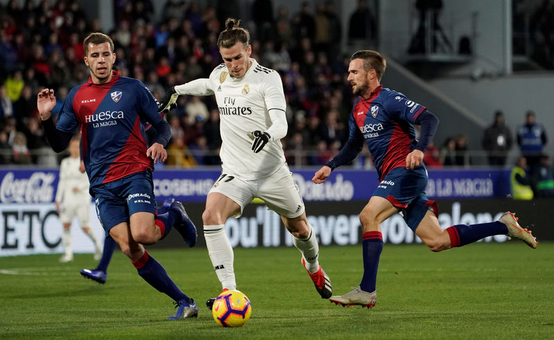 © Reuters. Gareth Bale del Real Madrid se prepara a patear el balón junto a Christian Rivera y Jorge Miramón de Huesca durante su partido de la liga española de fútbol disputado en el Estadio El Alcoraz, Huesca, España