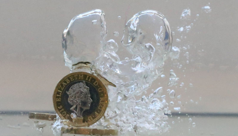 © Reuters. UK pound coins plunge into water in this illustration picture