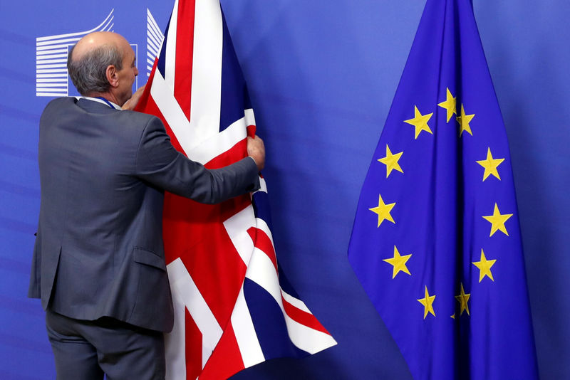 © Reuters. Nella sede della Commissione Ue, un impiegato sistema le bandiere del Regno Unito e dell'Unione