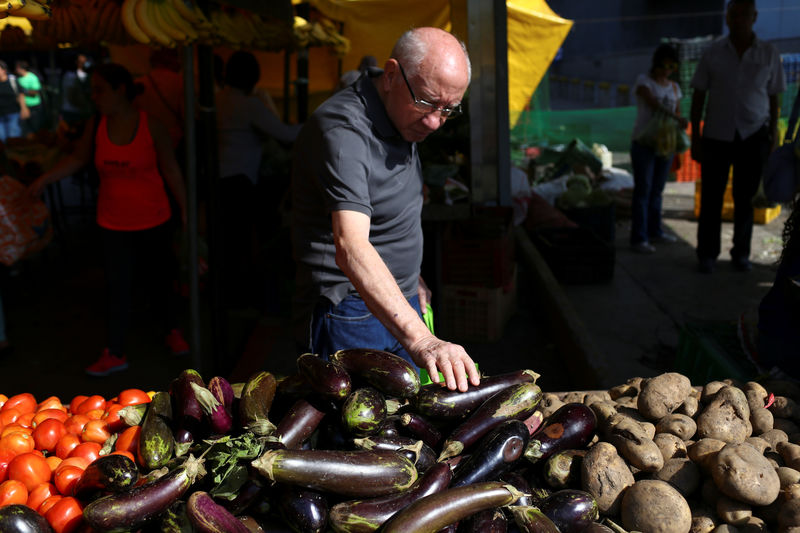 © Reuters. People shop at a vegetable and fruit stall at a street market in Caracas