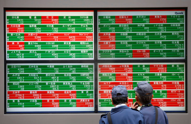 © Reuters. Men look at stock quotation boards outside a brokerage in Tokyo