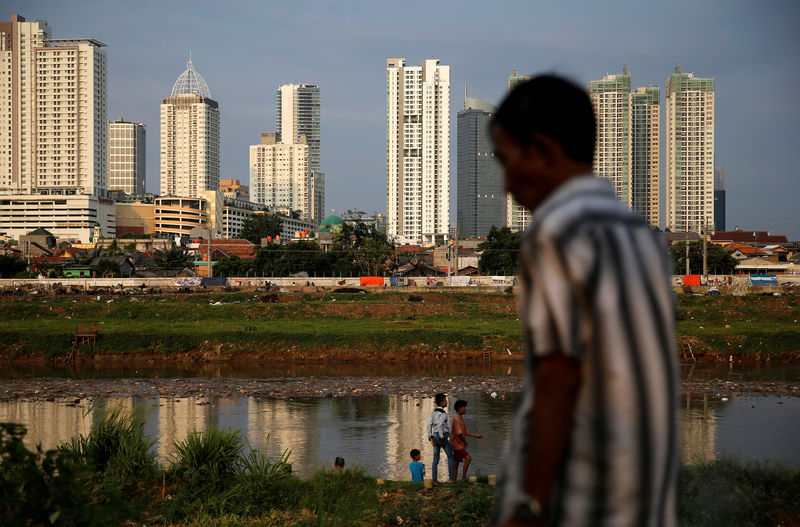 © Reuters. People stand at the Ciliwung river banks in Jakarta