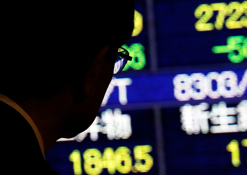 © Reuters. Мужчина смотрит на электронное табло с котировками акций в Токио
