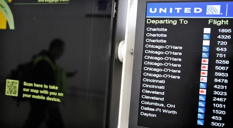 © Reuters. FILE PHOTO: A customer is reflected in a screen showing the schedule times of United at Newark International airport in New Jersey