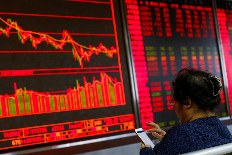 © Reuters. An investor sits in front of a board showing stock information at a brokerage office in Beijing
