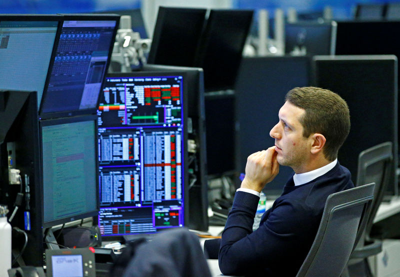© Reuters. Traders work at their desks whilst screens show market data at CMC Markets in London