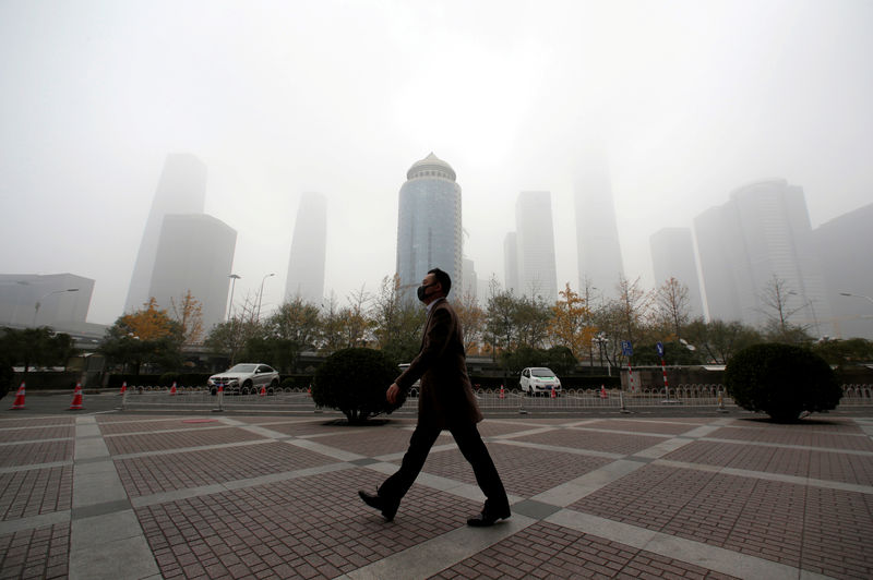 © Reuters. FILE PHOTO - Man wearing a mask walks in the central business district on a polluted day after a yellow alert was issued for smog, in Beijing