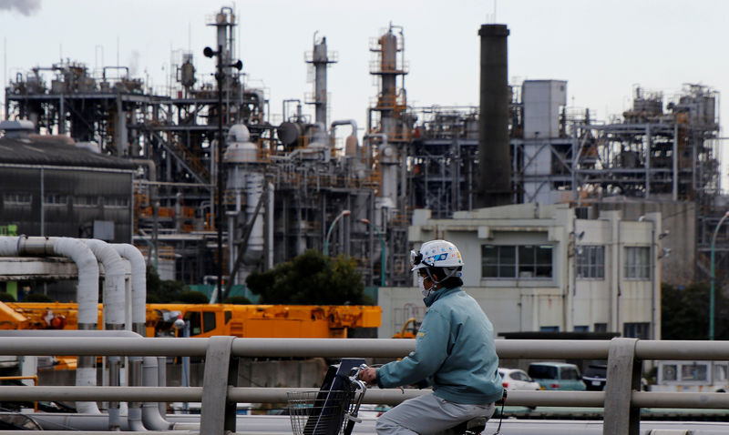 © Reuters. FILE PHOTO - Worker cycles near a factory at the Keihin industrial zone in Kawasaki,