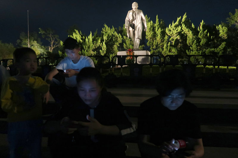 © Reuters. People sit on steps in front of the statue of the former Chinese leader Deng Xiaoping ahead of the 40th anniversary of China's reform and opening up in Shenzhen