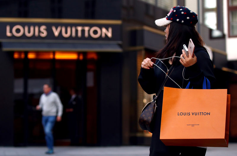 © Reuters. Woman with a Louis Vuitton-branded shopping bag looks towards the entrance of a branch store by LVMH Moet Hennessy Louis Vuitton in Vienna