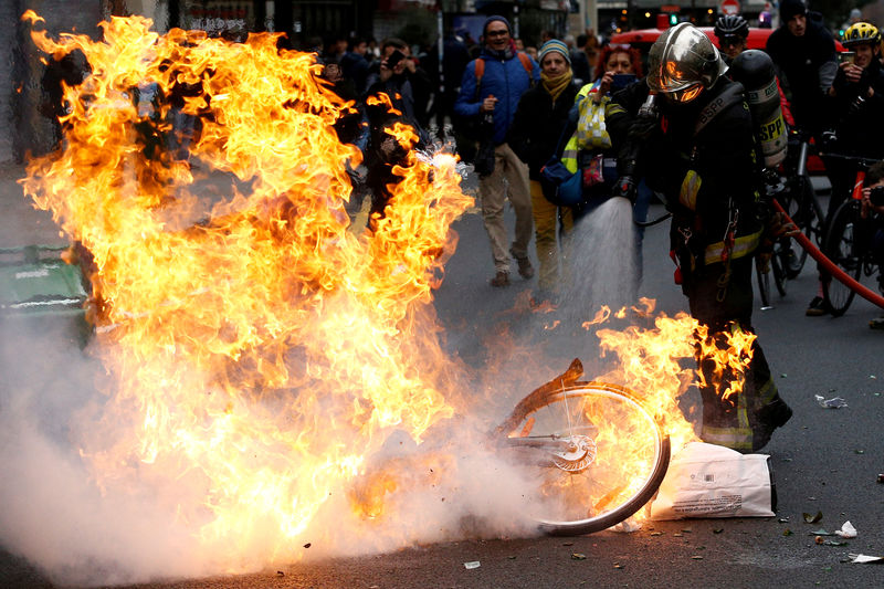 © Reuters. FILE PHOTO: A fireman extinguishes a burning bicycle during clashes with yellow vests protesters as part of a national day of protest by the "yellow vests" movement in Paris