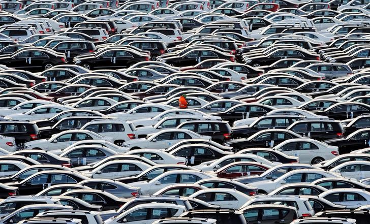 © Reuters. FILE PHOTO: A worker walks along rolls of Mercedes cars at a shipping terminal in the harbor of the town of Bremerhaven