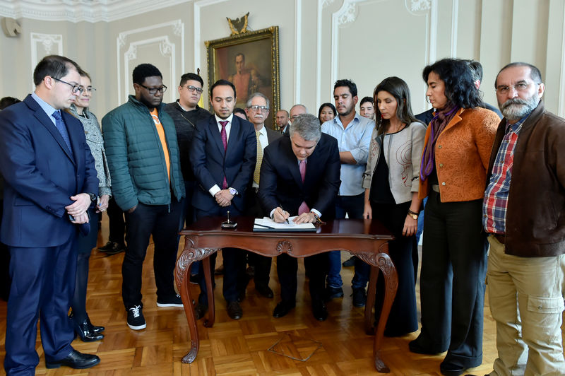 © Reuters. Colombian President, Ivan Duque, signs the financing agreement for public education accompanied by the student leaders in the presidential palace of Bogota