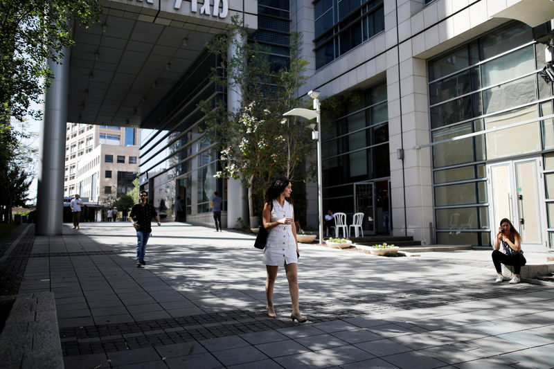 © Reuters. FILE PHOTO: A woman walks near high-rise buildings in the high-tech business area of Tel Aviv, Israel
