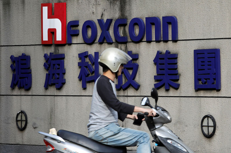 © Reuters. FILE PHOTO: A motorcyclist rides past the logo of Foxconn, the trading name of Hon Hai Precision Industry, in Taipei