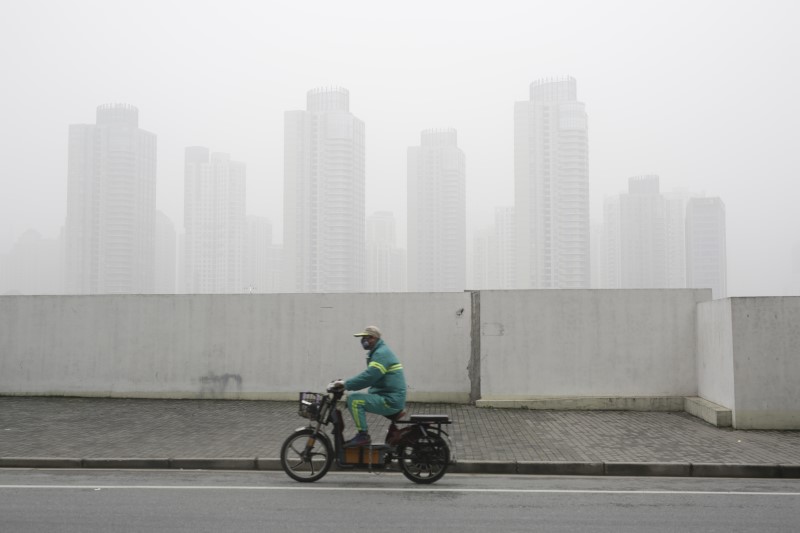 © Reuters. A man wearing a face mask rides an electric bicycle near the financial district of Pudong amid heavy smog in Shanghai