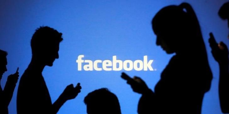 © Reuters. Pessoas utilizam celulares diante de projeção do logo do Facebook em foto ilustrativa